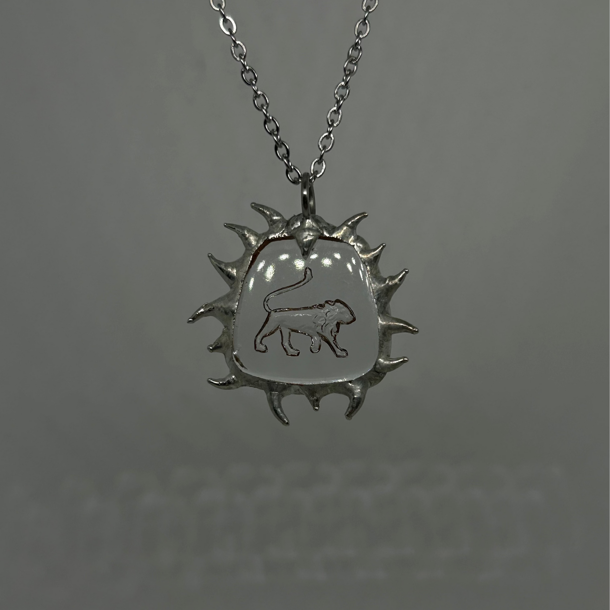 Silver necklace with a sun-shaped pendant featuring a lion emblem
